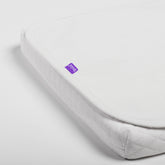 White mattress cover with a purple label on a light gray background